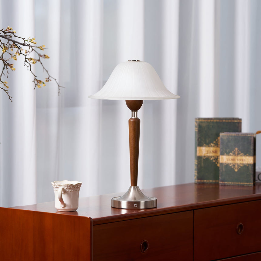 Nightstand table lamp lit on a cherry chest beside two old bound books