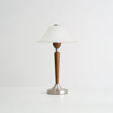 Nightstand table lamp seen from the side against a plain pale ground