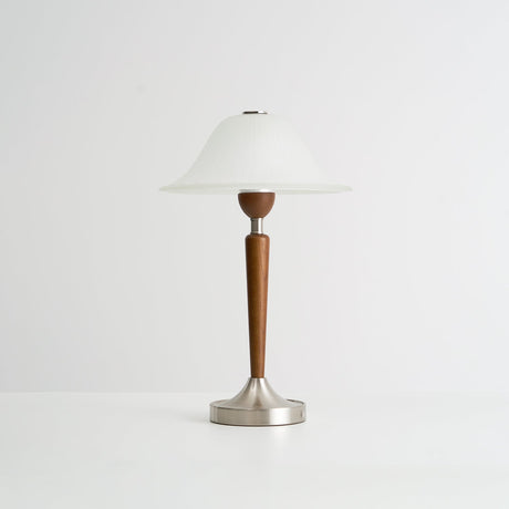 Nightstand table lamp seen from the side against a plain pale ground