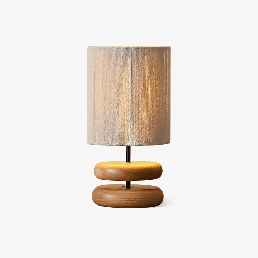 Nightstand table lamp on two wood pebbles against a plain background