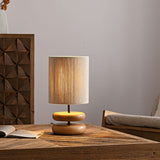 Wood pebble nightstand table lamp on a table against a carved panel