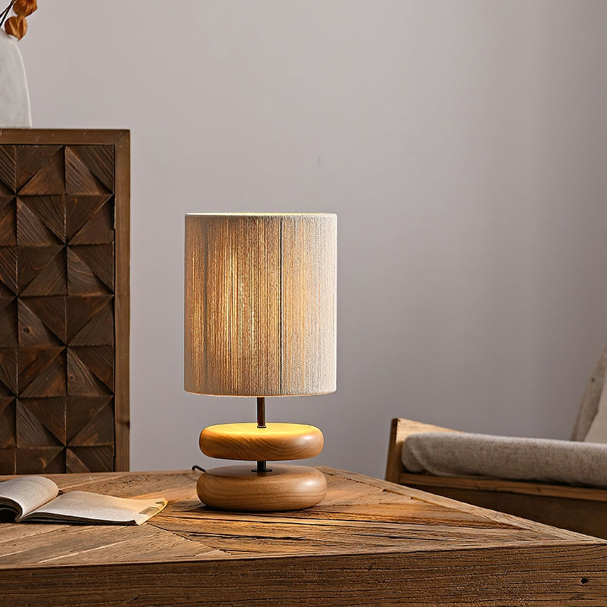 Wood pebble nightstand table lamp on a table against a carved panel