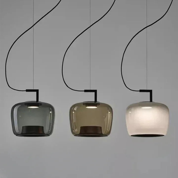 Green, smoky white and amber glass shades hung in a row against gray