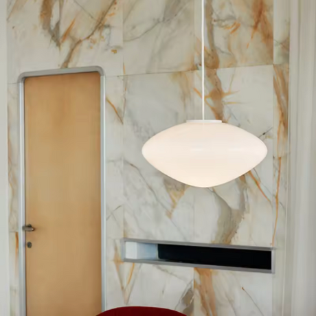 The pebble shade lit in a hallway against a marble wall and a door