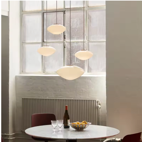 Three opal pebble shades lit above a round dining table by a window