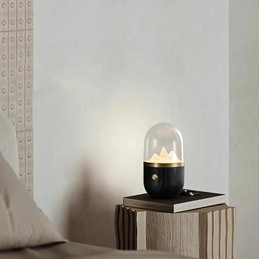 Black based nursery table lamp lit on a book on a stone side table