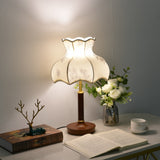 Blossom shade lamp lit on a desk beside a bonsai and an open book