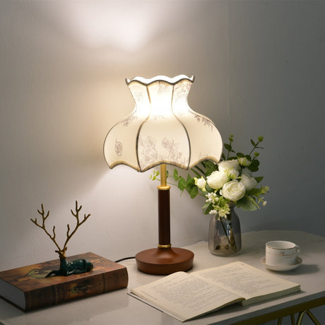 Blossom shade lamp lit on a desk beside a bonsai and an open book