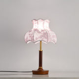 Pink blossom shade lamp on a plain ground with a wood disc base