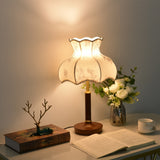 White blossom shade lamp lit warm beside roses and an open book
