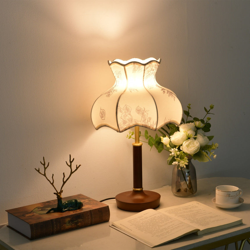 White blossom shade lamp lit warm beside roses and an open book