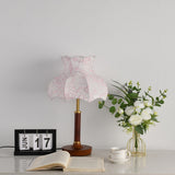 Pink blossom shade lamp unlit beside white roses in a glass vase