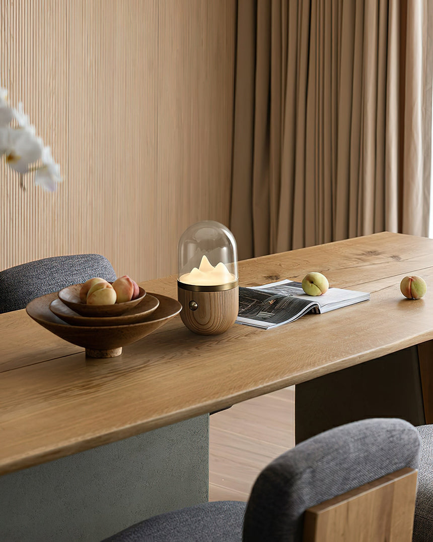 Nursery table lamp lit on a long wooden desk beside a bowl of fruit