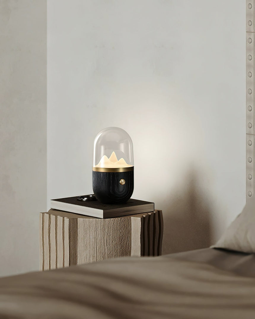 Nursery table lamp lit on a stone plinth beside a bed
