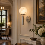 The lit globe beside framed art above a console with white flowers