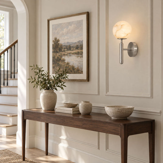 The lit globe above a console with a vase and bowls near a staircase