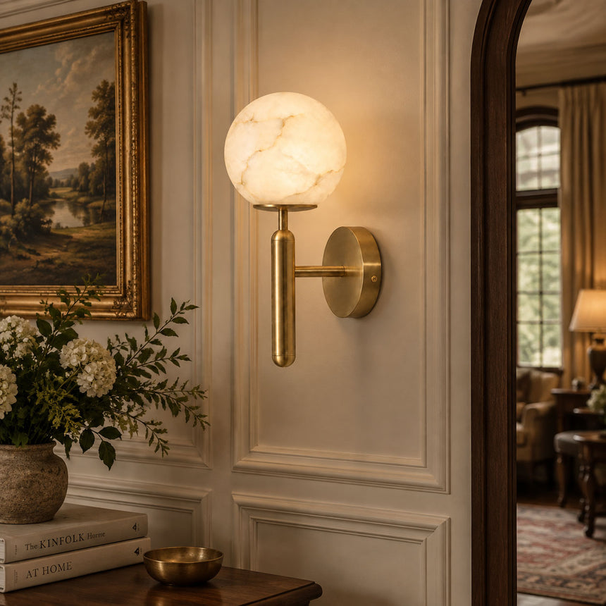 The lit globe on a paneled wall beside a landscape painting and flowers