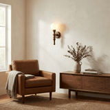 Sconce lit beside a leather armchair and a sideboard with dried branches