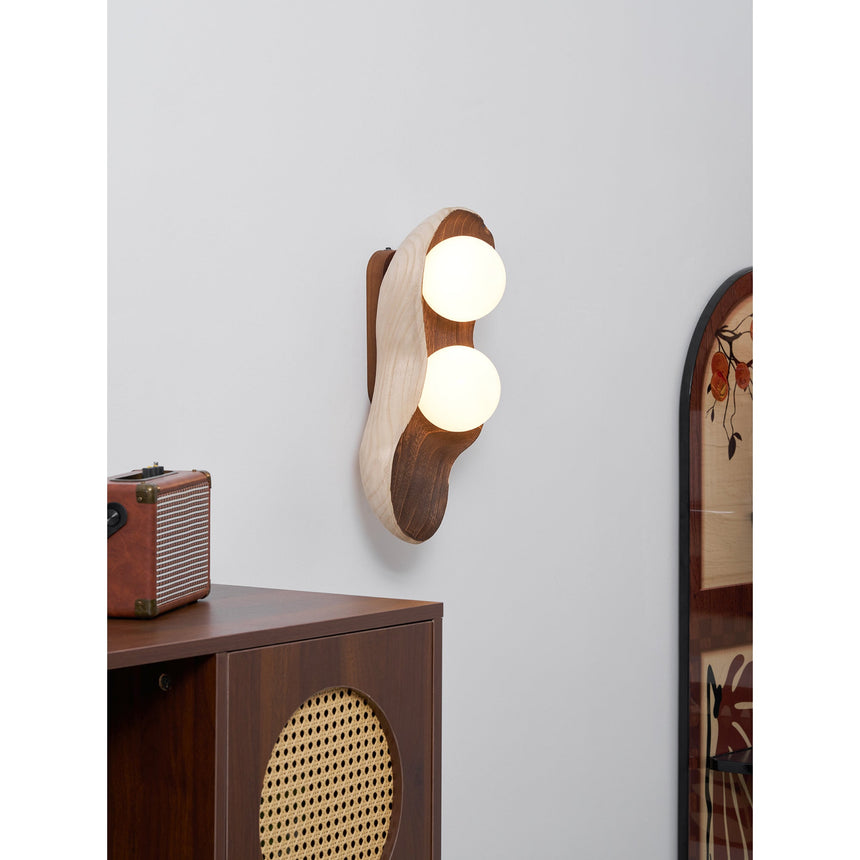 Sconce lit above a cane panel cabinet beside a framed print on the wall