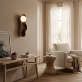 Sconce lit above a console beside an armchair and a round side table