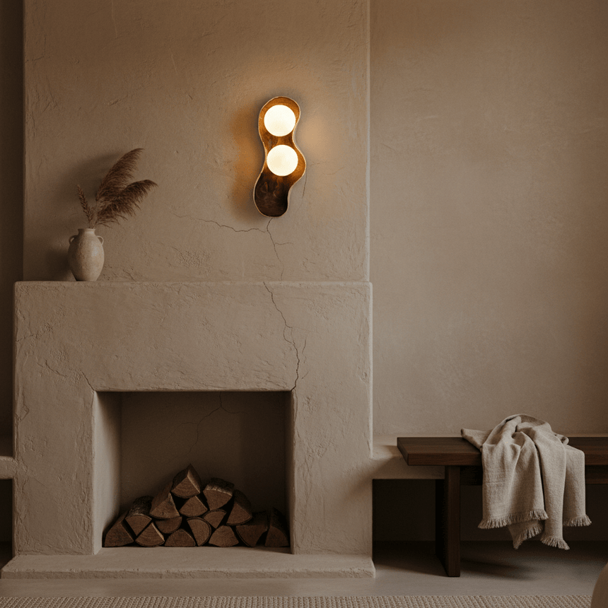 Sconce lit on a plaster wall above a fireplace stacked with split logs