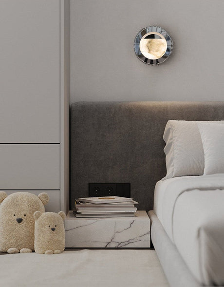 The orbit light lit above a bed with a gray headboard and a marble nightstand