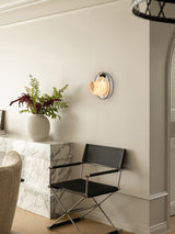 The orbit light lit above a leather chair beside a stone console with a vase