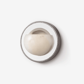 Round wall light with an alabaster half bowl set in a mirrored ring with a beaded rim
