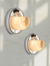 Two orbit lights lit on a pale plaster wall