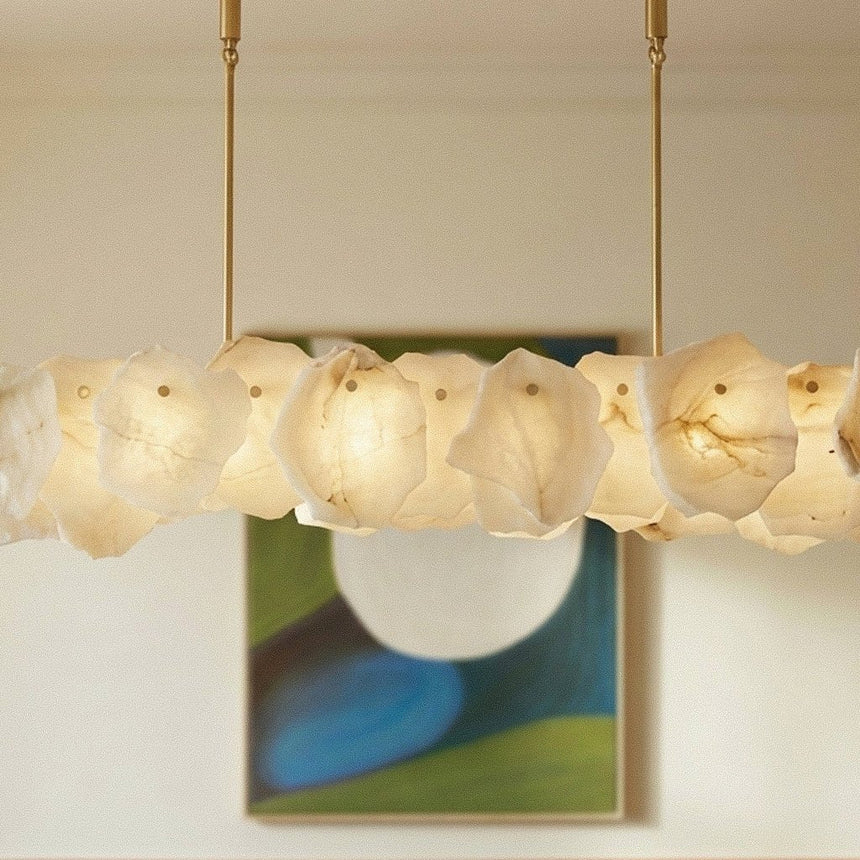 A lit petal bar above a framed painting on a pale wall