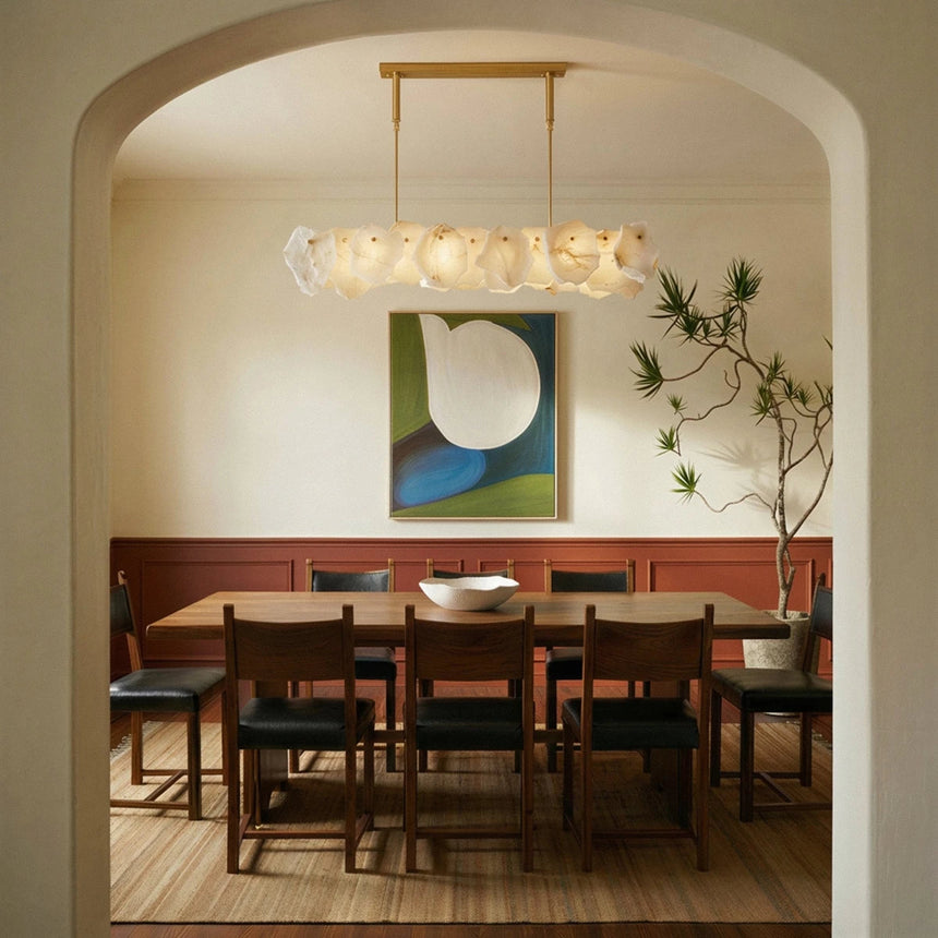 A petal bar lit above a dining table seen through a plaster arch
