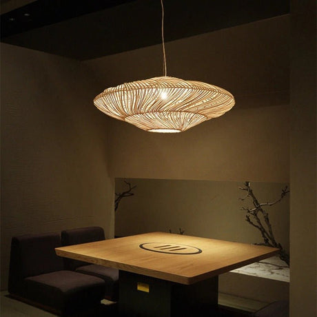 The black shade lit beside a paneled window with a low table and cups below