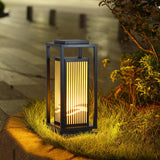 The cage lantern lit among low planting at the edge of a garden path