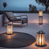 Lanterns lit on a terrace around a dark round rug beside a lounger