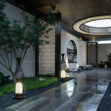 The lantern lit in a courtyard beside a small tree and a screen