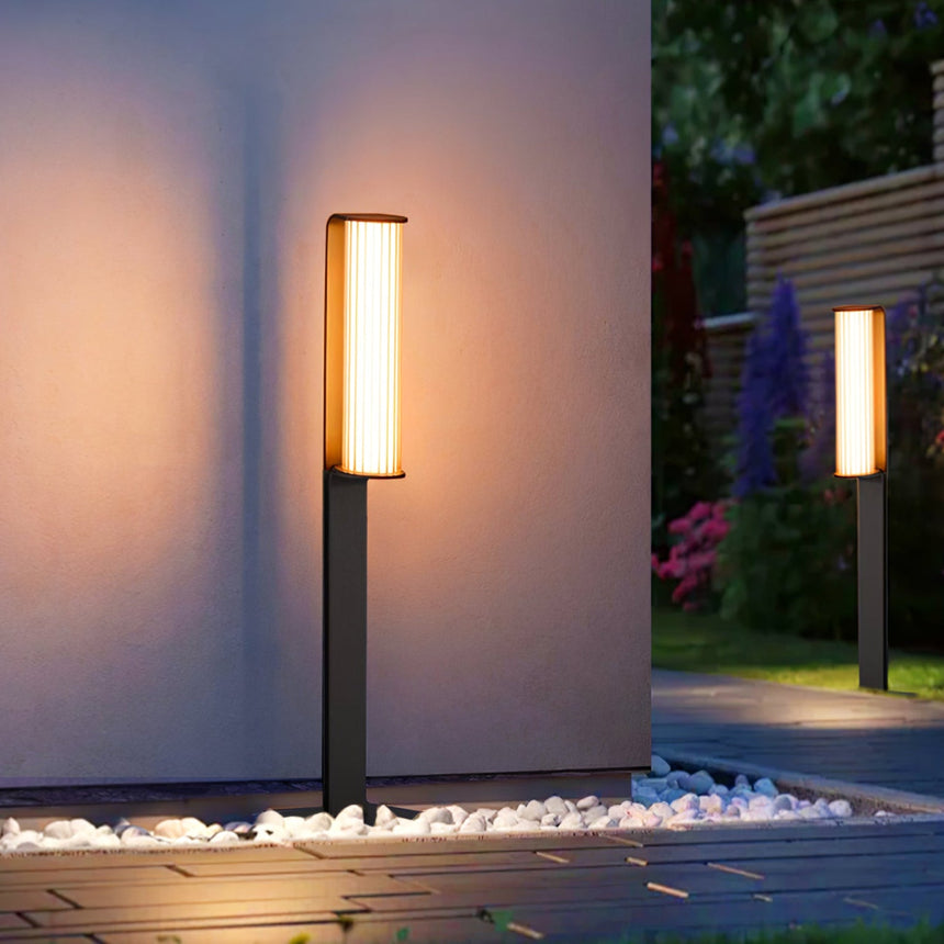 The tube glowing against a pale render wall above white pebbles