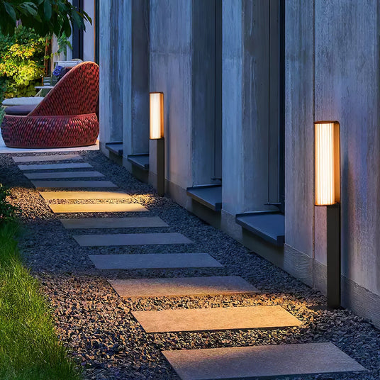 Two lit beside a stepping stone path against a concrete garden wall