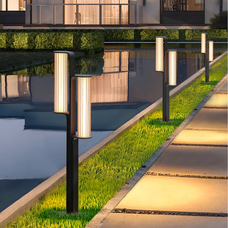 A run lit along a water channel beside a lawn and pale paving slabs