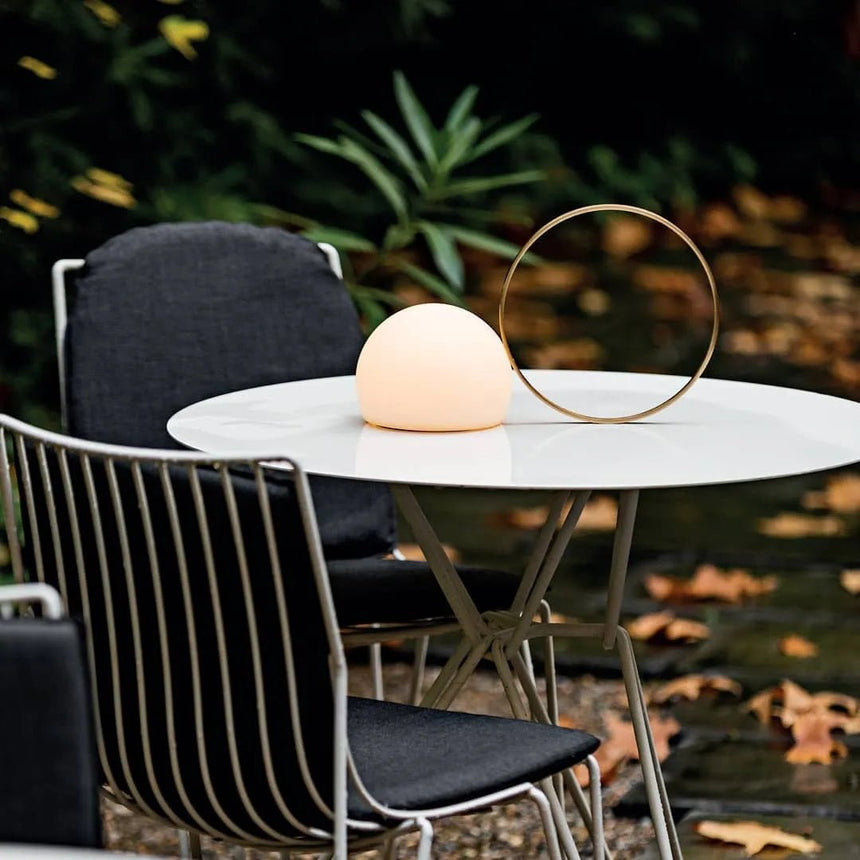 Lit on a white garden table with black chairs and fallen leaves