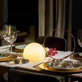 Lit on a laid dinner table beside wine glasses and folded napkins
