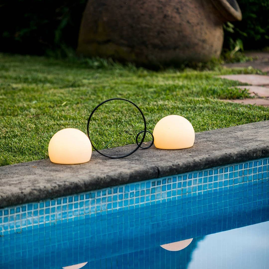 Two sizes lit on grass at the edge of a lit swimming pool