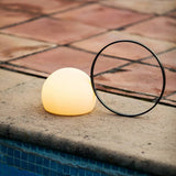 Lit on terracotta poolside paving beside blue mosaic water