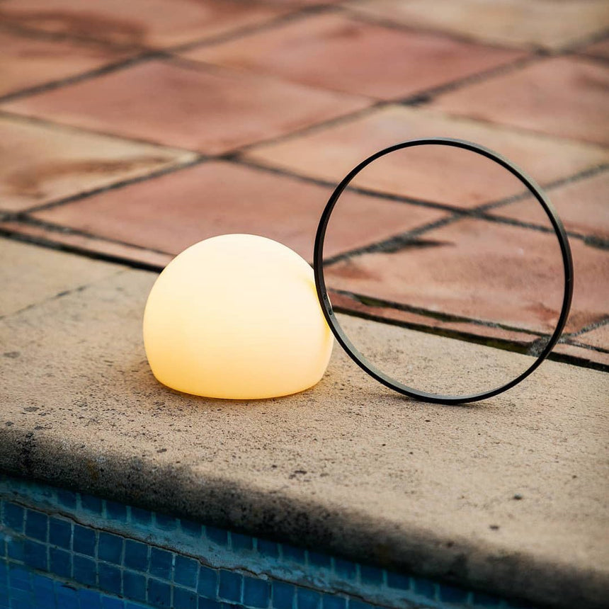 Lit on terracotta poolside paving beside blue mosaic water