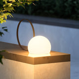 The lamp lit on a pale stone block in a walled garden at dusk