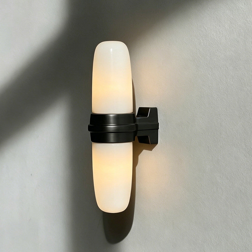 The black bracket and lit tube seen at an angle on a pale wall