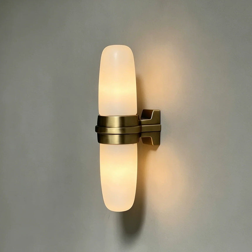 The brass bracket and lit stone tube seen against a gray wall