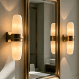 The sconce lit beside a tall gold framed mirror in a bright room