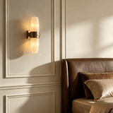 The sconce lit on a paneled wall above a brown leather sofa