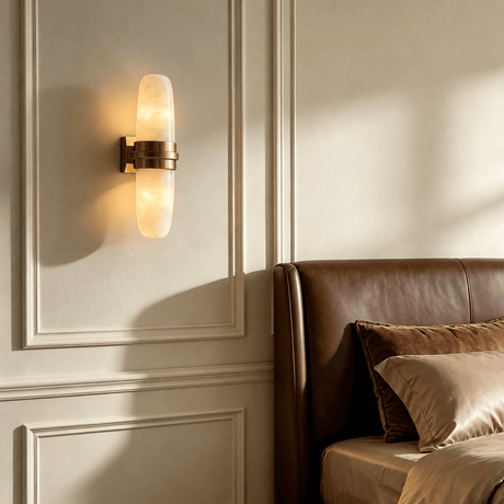 The sconce lit on a paneled wall above a brown leather sofa