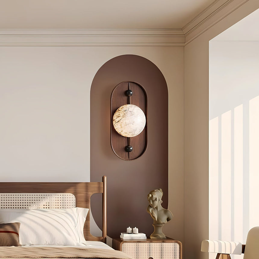 Sconce lit above a bed with cane cushions and a nightstand beside it